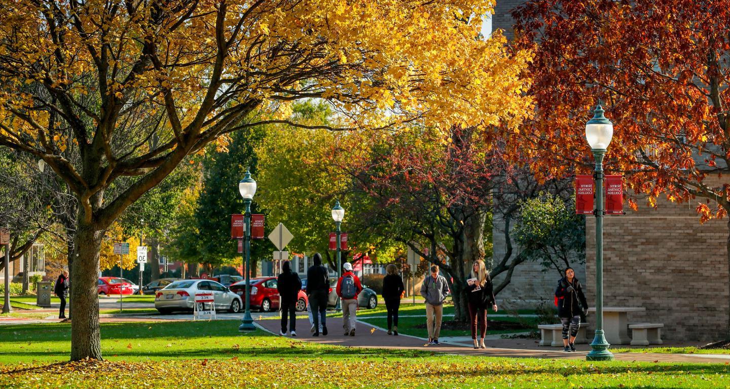 学生 walking on campus in the fall